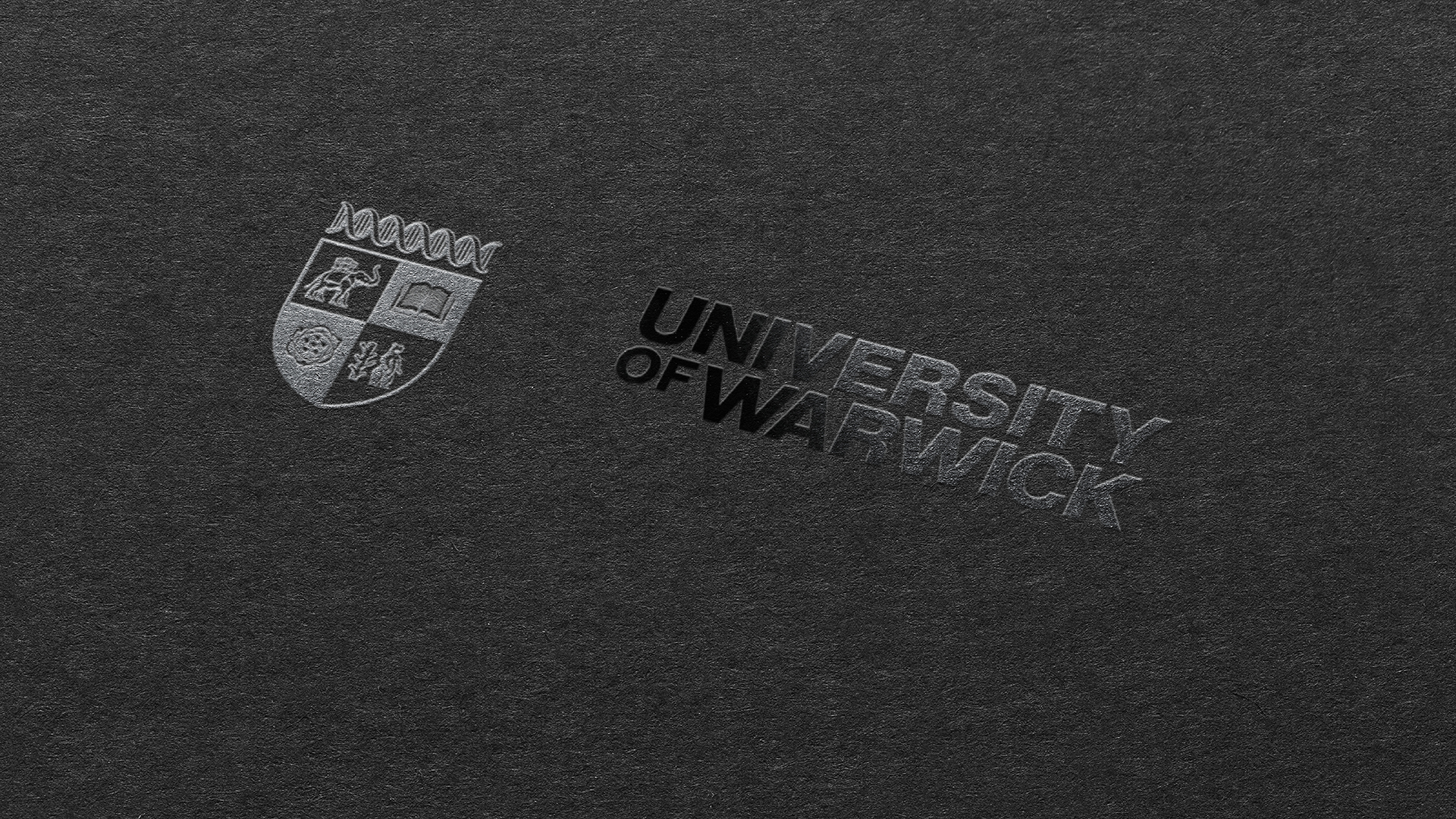 Embossed University of Warwick text and crest on a black background