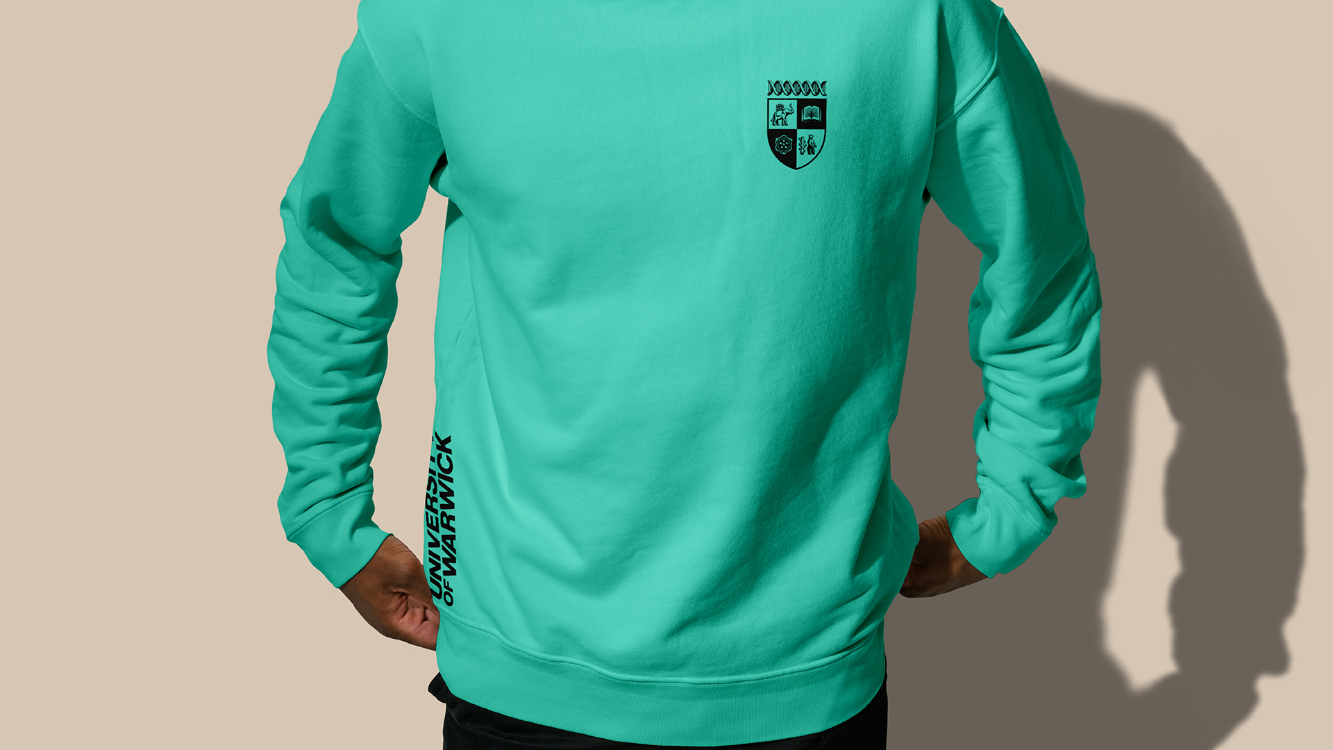 Person wearing green jumper featuring University of Warwick text and crest