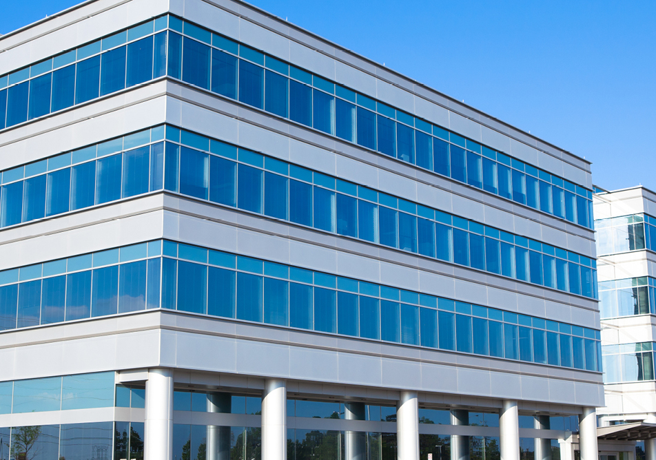 A white building building photographed straight on against a blue sky, the windows reflect the sky giving a very flat colour palette
