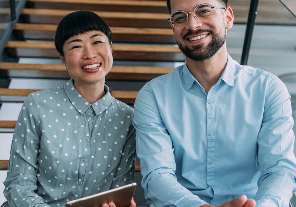 Two people sitting on stairs smiling at the camera