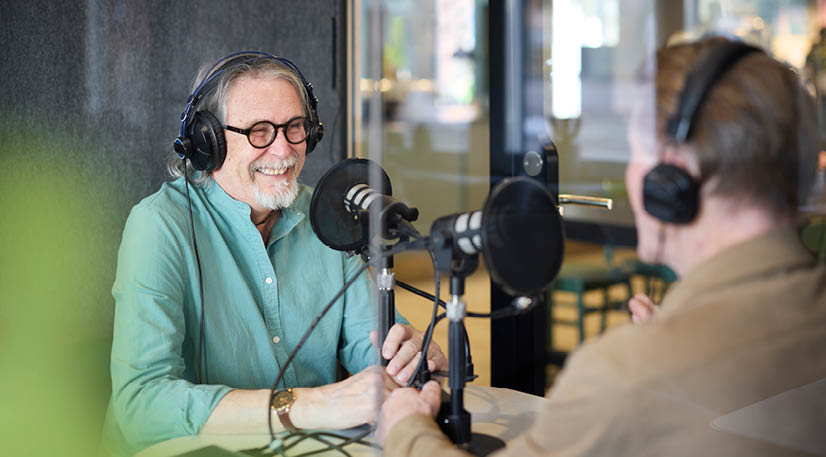Two males sitting together in a recording studio taking part in a podcast