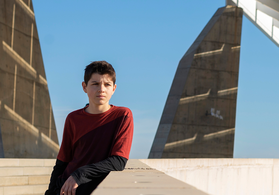 A person leans on a concrete wall with concrete shapes and interesting shadows in the background 