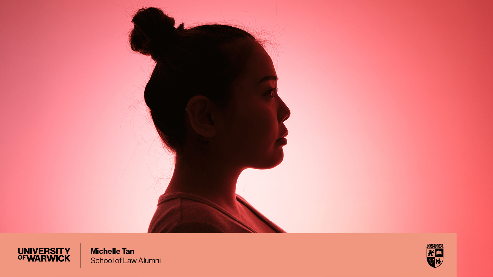 A side-profile silhouette of a woman against a pink-red gradient background. A branded lower third graphic bar appears at the bottom, featuring the University of Warwick logo on the left, the name ‘Michelle Tan’ with the title ‘School of Law Alumni’ in the centre, and the university crest on the right.