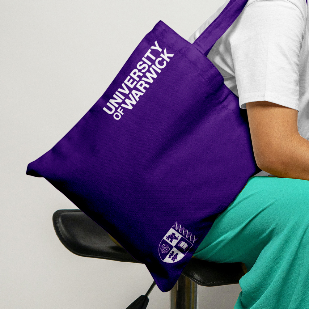 A purple tote bag branded with University of Warwick wordmark and crest.